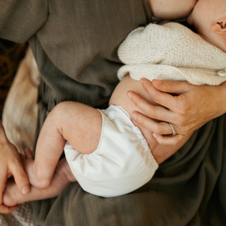 Nyfødt baby bliver ammet og har en Weecare nyfødt stofble på i farven Pearl