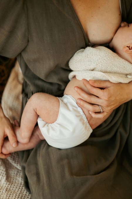 Nyfødt baby bliver ammet og har en Weecare nyfødt stofble på i farven Pearl